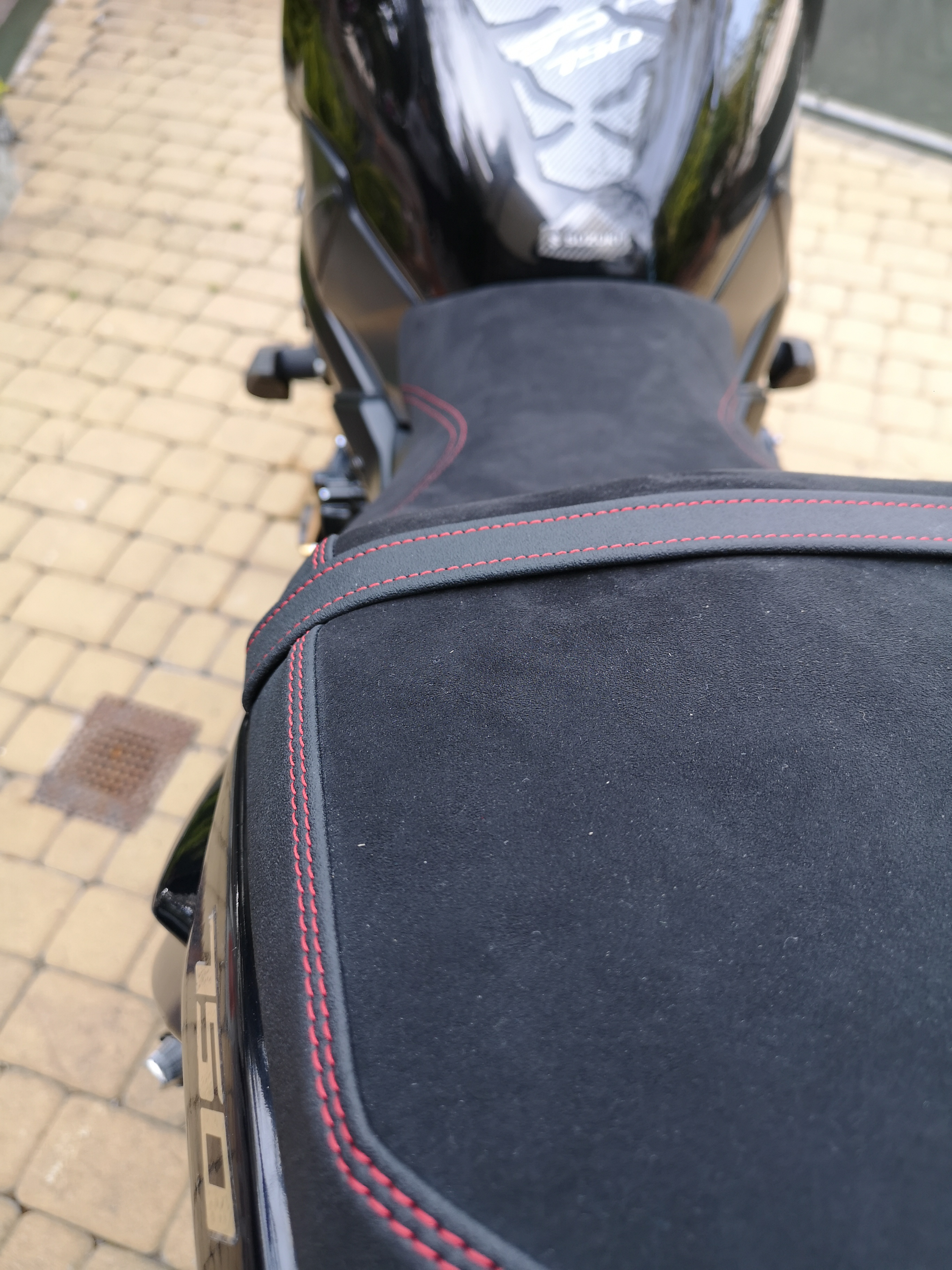 Detal czerwonego szwu na siedzeniach Suzuki GSR 750 obszytych alcantarą i czarnym winylem