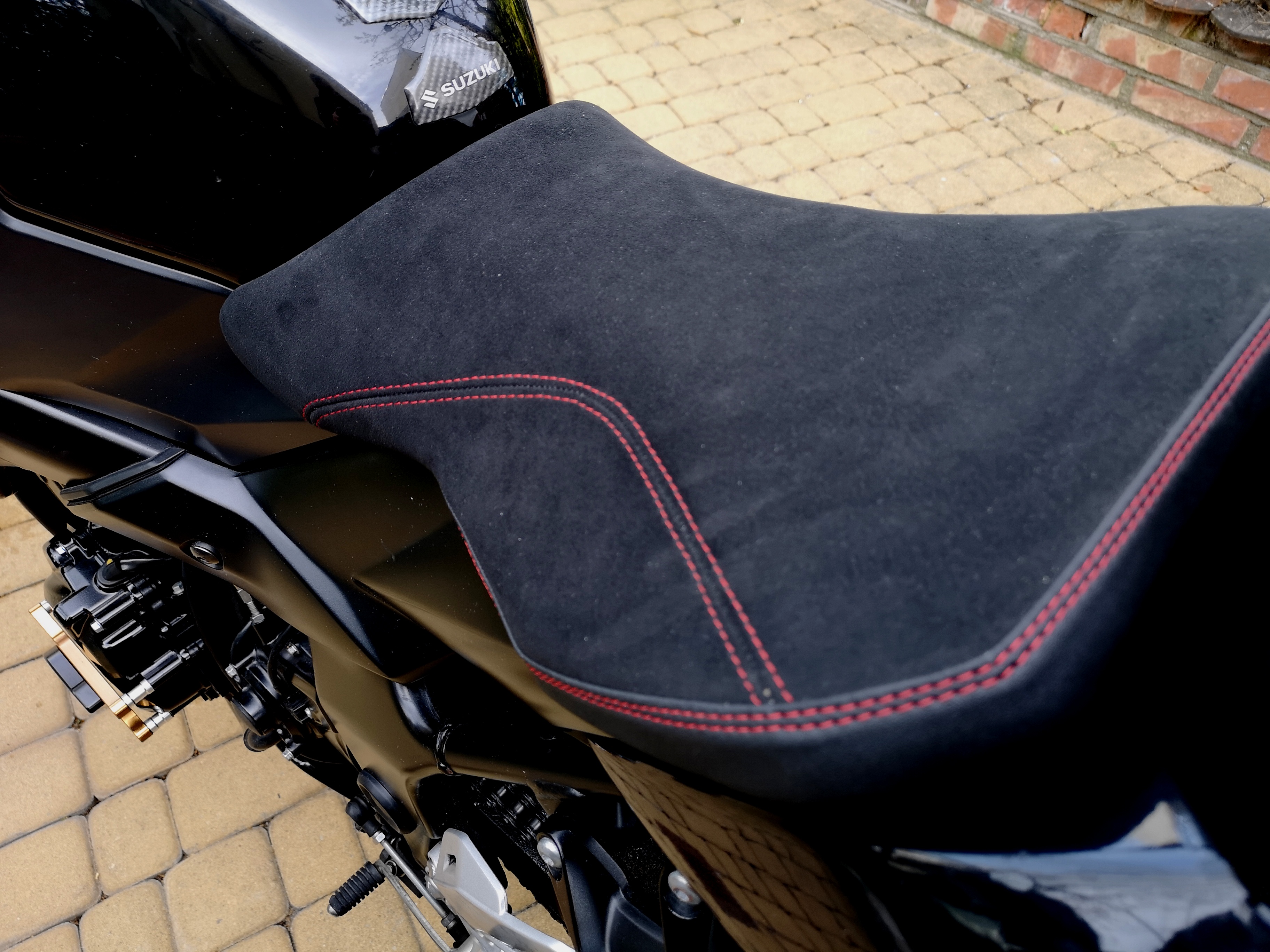Przednie siedzenie Suzuki GSR 750 obszyte czarną alcantarą z winylową lamówką i czerwoną nicią